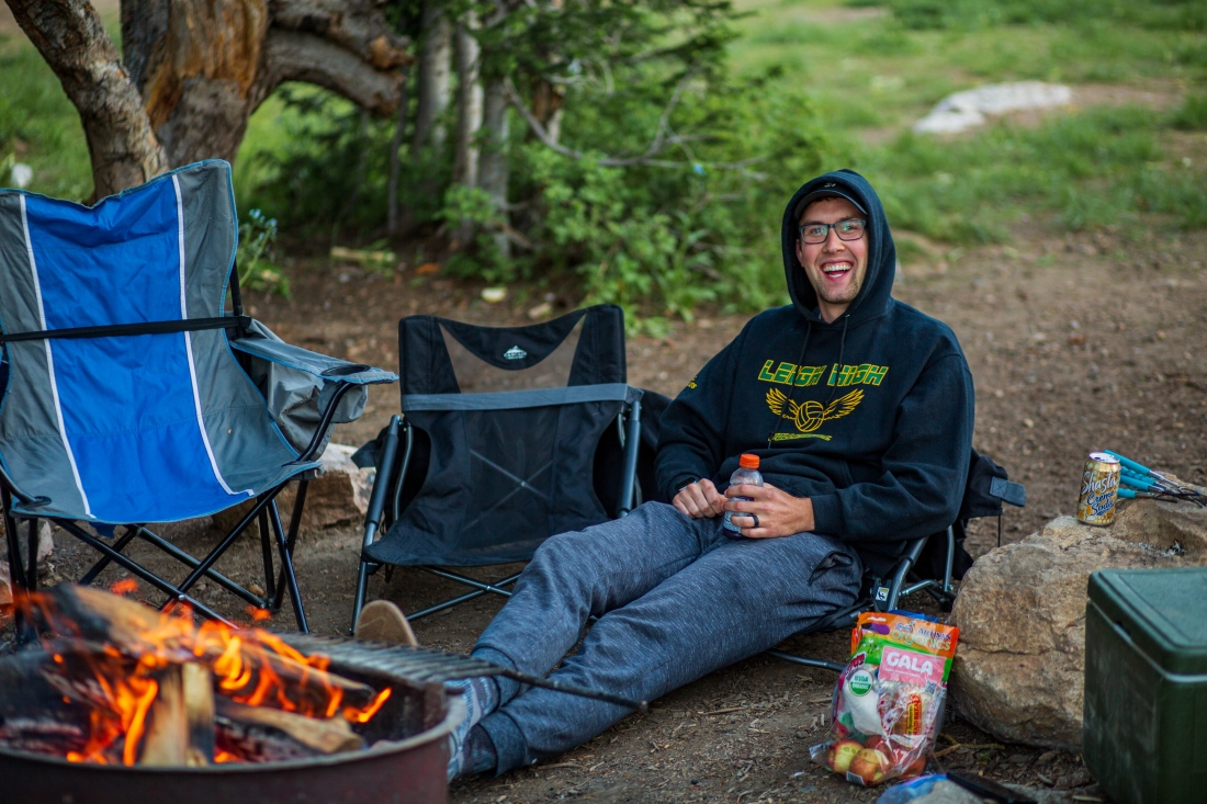 Smiling young man sitting around the campfire